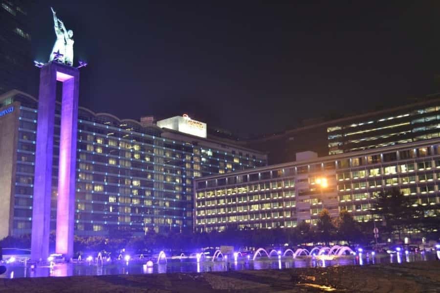 Jakarta: Private Guided Sightseeing & Street Food Night Tour - The National Monument glowing above the city